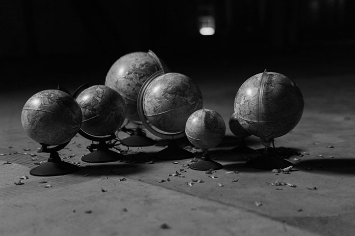 Six geographic globes of various sizes on cement floor